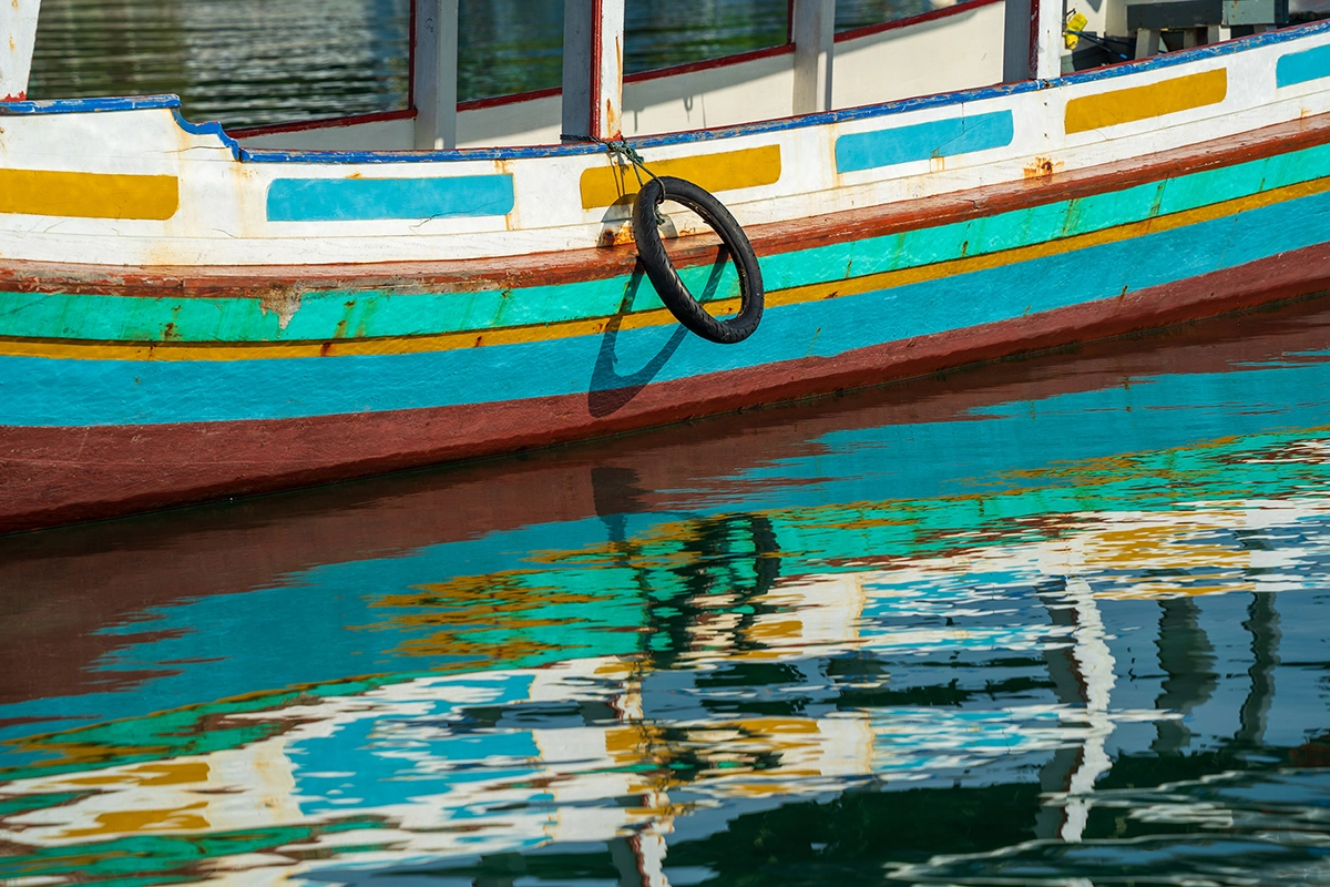 Colorful boat hull and reflection on water illustrating how lens choice shapes composition and creative perspective.