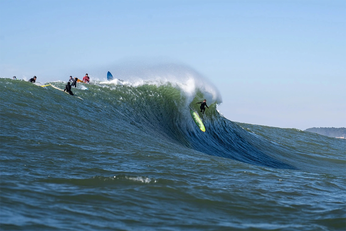 Fotografía de surf de un surfista lanzándose a una gran ola rompiendo en Mavericks, en Half Moon Bay, California.