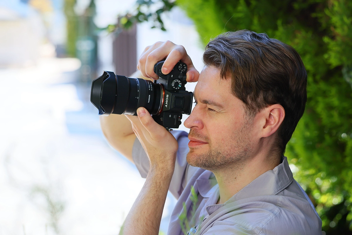 Photographe utilisant l'objectif Tamron 16-30mm F/2.8 Di III VXD G2 sur un appareil photo sans miroir Sony en extérieur.