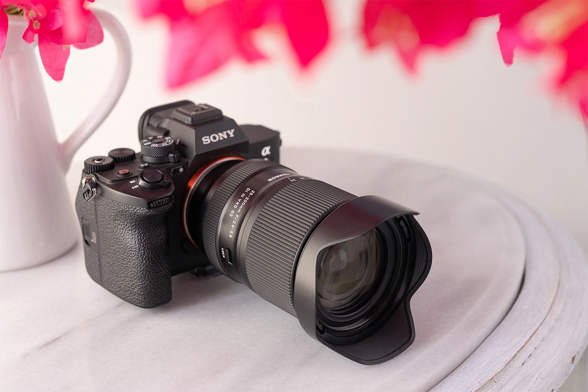Objectif Tamron 25-200 mm F/2,8-5,6 Di III VXD G2 (modèle A075) monté sur un appareil photo sans miroir Sony posé sur une table.