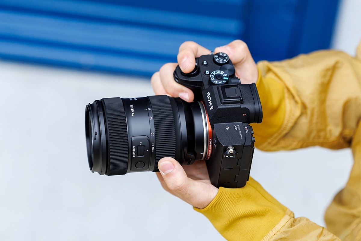 Objectif Tamron 35-100mm F/2.8 Di III VXD (modèle A078) monté sur un appareil photo sans miroir Sony tenu en main.