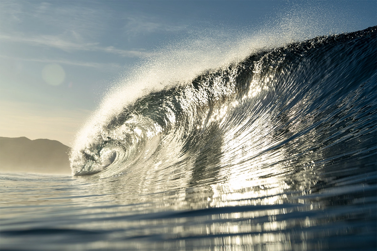 Fotografía de una ola tubular resplandeciente rompiendo al amanecer en la playa de Cerritos, en Baja California.