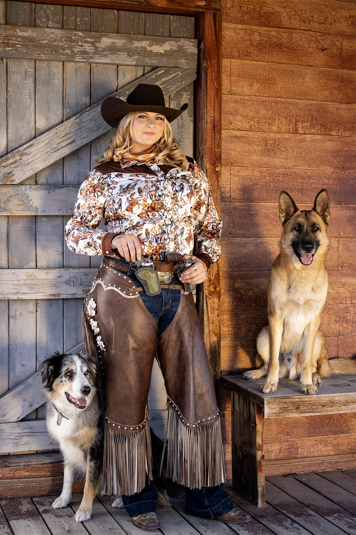 Vaqueira em pé com dois cães fotografada com a lente Tamron 35-100 mm F/2.8 Di III VXD.