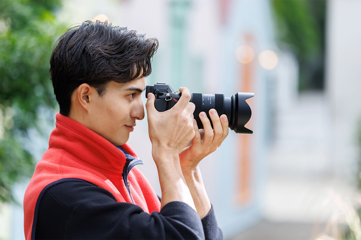 Fotógrafo usando a lente Tamron 35-100 mm F/2.8 Di III VXD com zoom para retrato em uma câmera sem espelho.