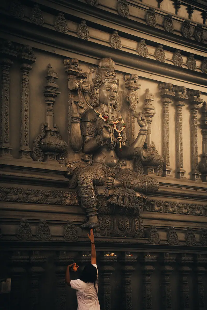 The Mayurapathy Sri Bathrakali Hindu temple, near Colombo, with a woman reaching up to touch the statue's foot.