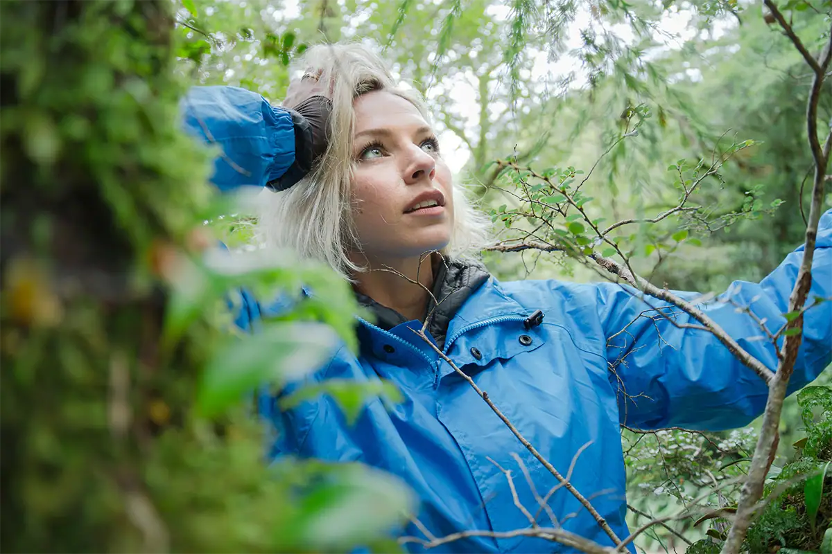 Mujer en un paisaje forestal al aire libre, bajo una suave luz natural, en un retrato ambiental tomado a primera hora de la mañana.