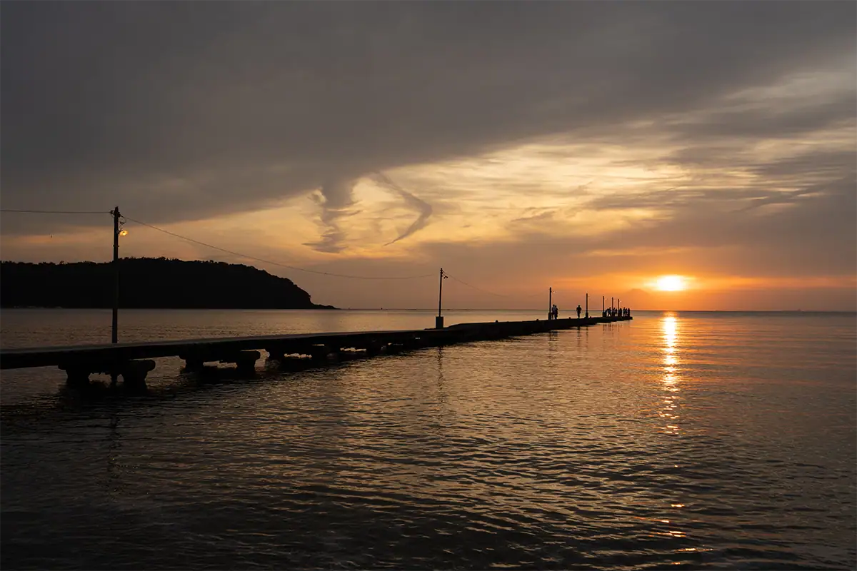 Escena a contraluz al atardecer, con una luz cálida reflejándose en el agua.
