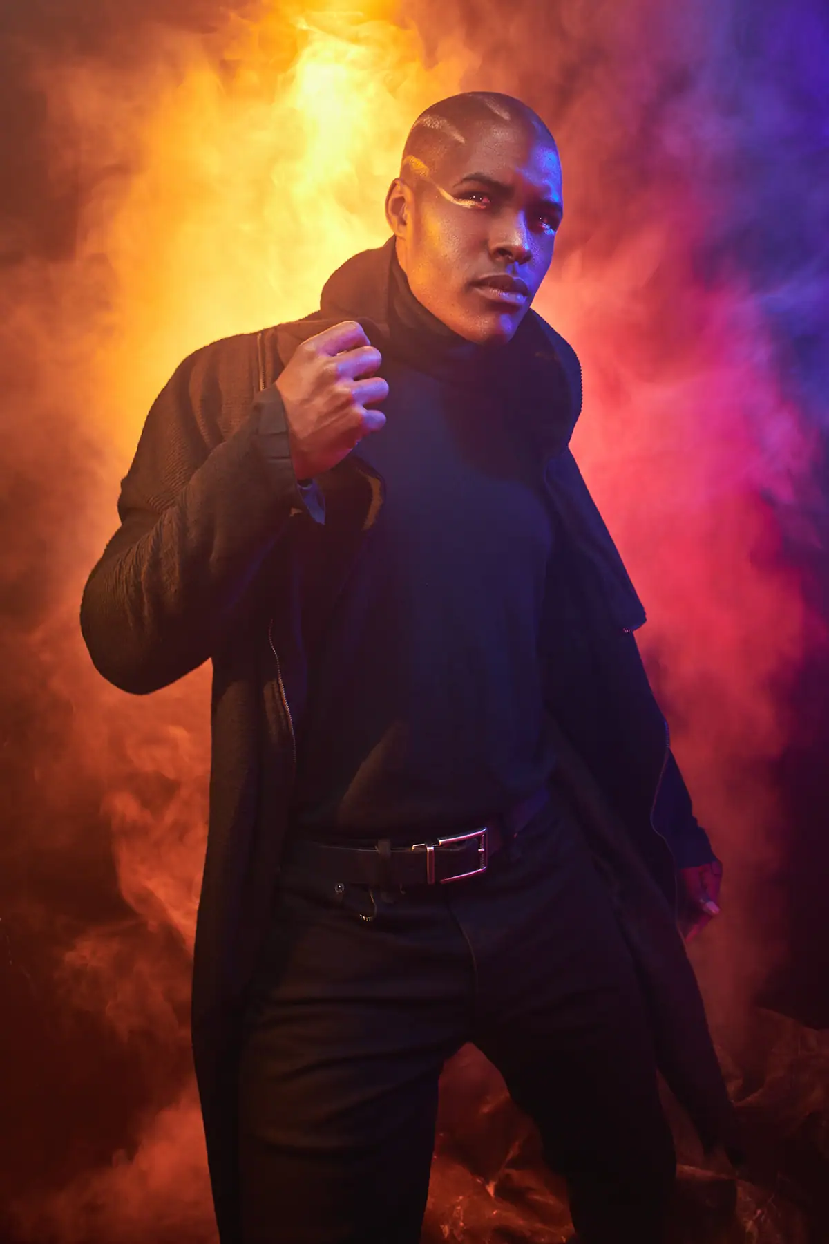 Retrato de una modelo rodeada de humo naranja y azul, iluminada con geles de colores vivos.