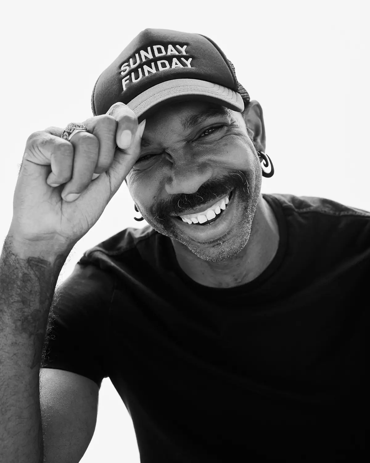 Retrato en blanco y negro de un hombre sonriente con gorra, con una luz expresiva y una fuerte personalidad.