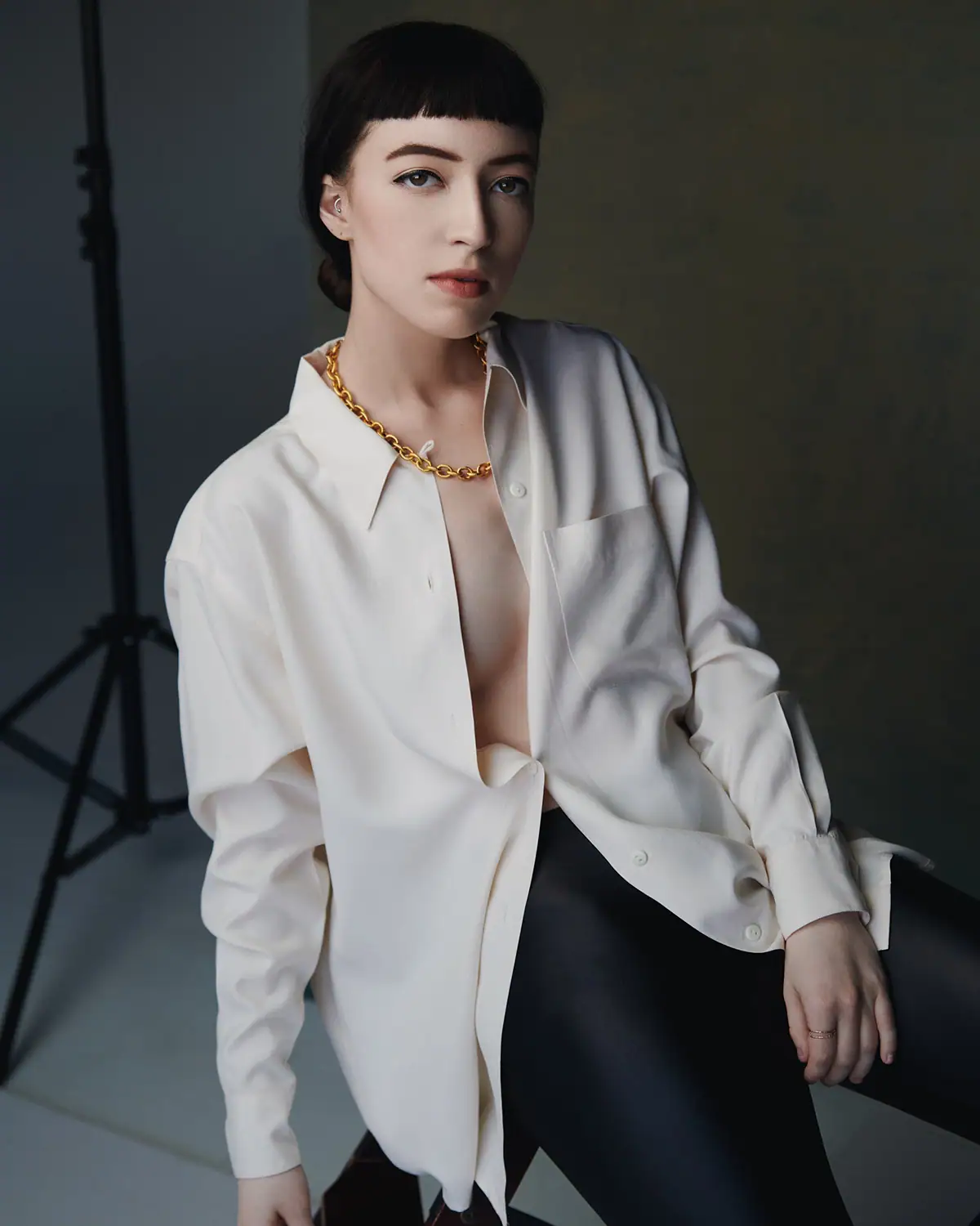 Retrato de estudio de una mujer con una camisa blanca, iluminada con una luz direccional refinada para lograr un look de moda elegante.