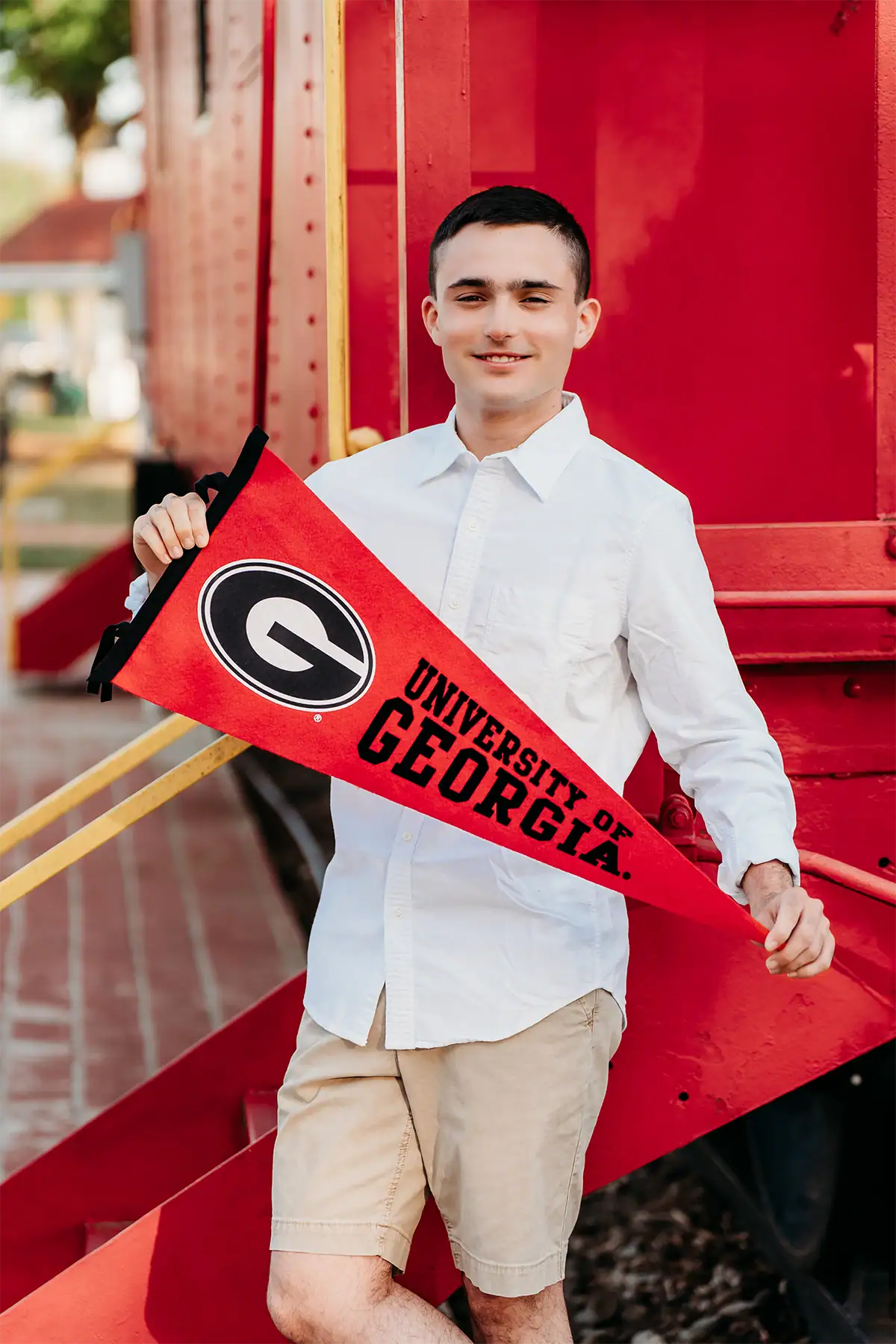 Un estudiante de último año de secundaria sostiene un banderín de la Universidad de Georgia durante una sesión de fotos de graduación.