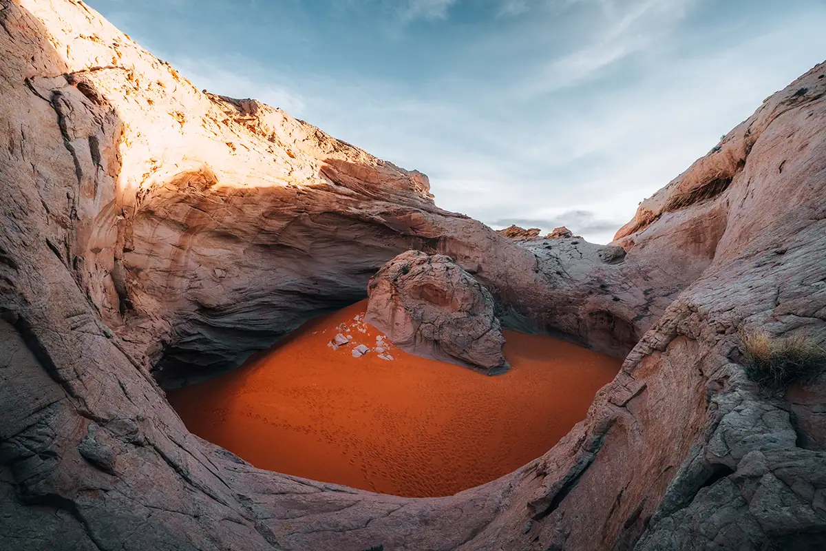 A carved-out section of rock with bright orange sand inside.