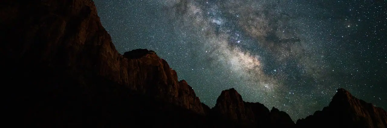 Milky Way above silhouetted mountains for an astrophotography camera settings guide.
