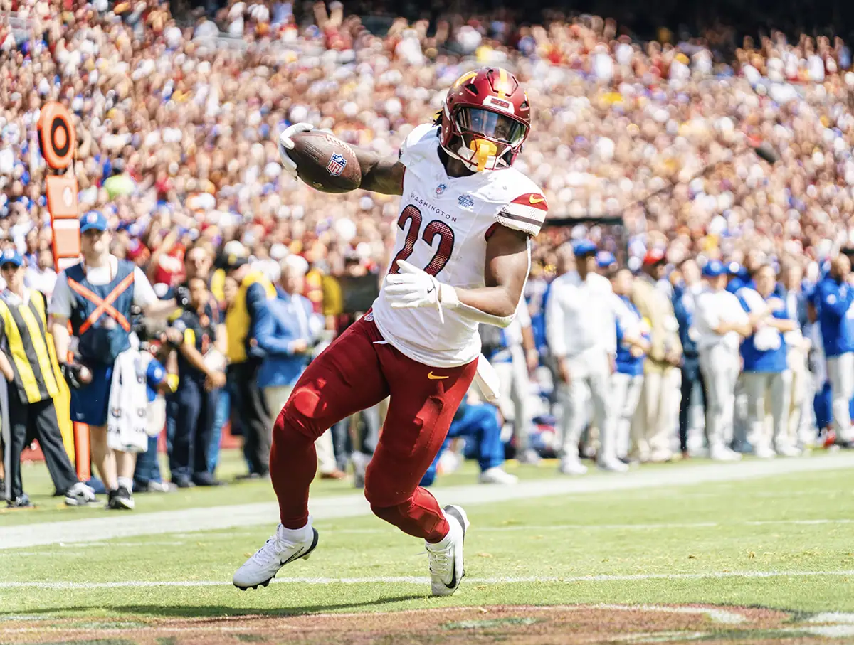 A football player runs with the ball while the crowd behind him is softly blurred.
