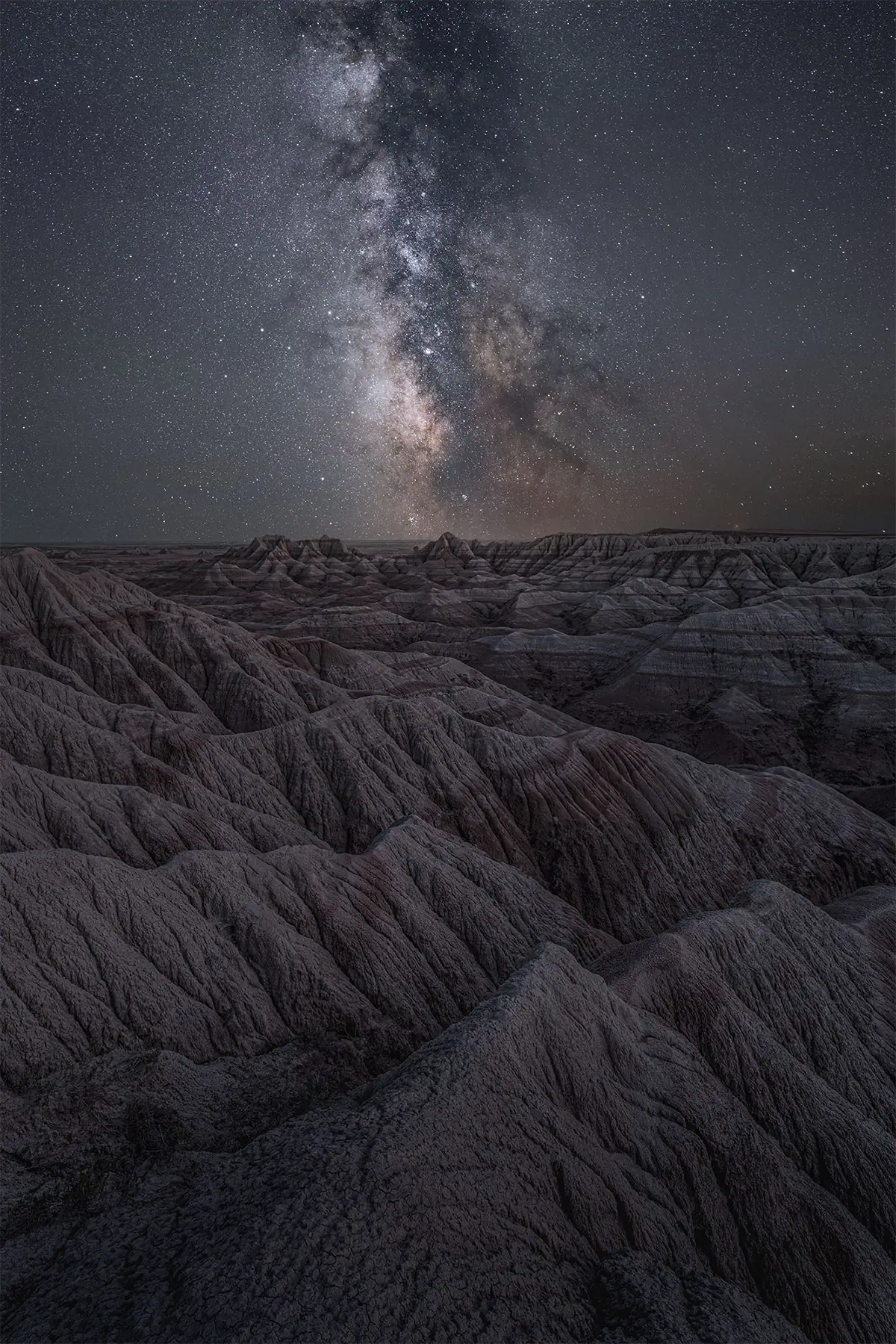 Milky Way galactic core above the Badlands with a strong foreground landscape.