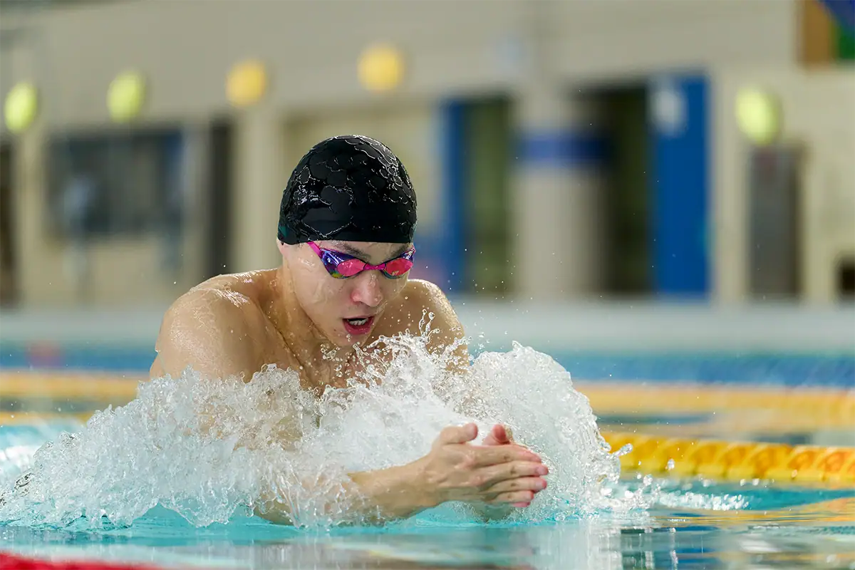 A swimmer moves through the water during an indoor race with a softly blurred background.