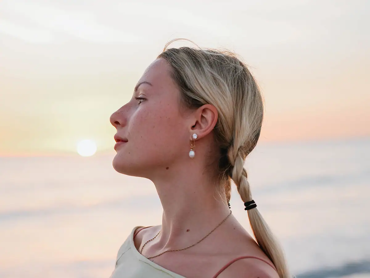Close-up portrait of a woman on the beach at sunset.