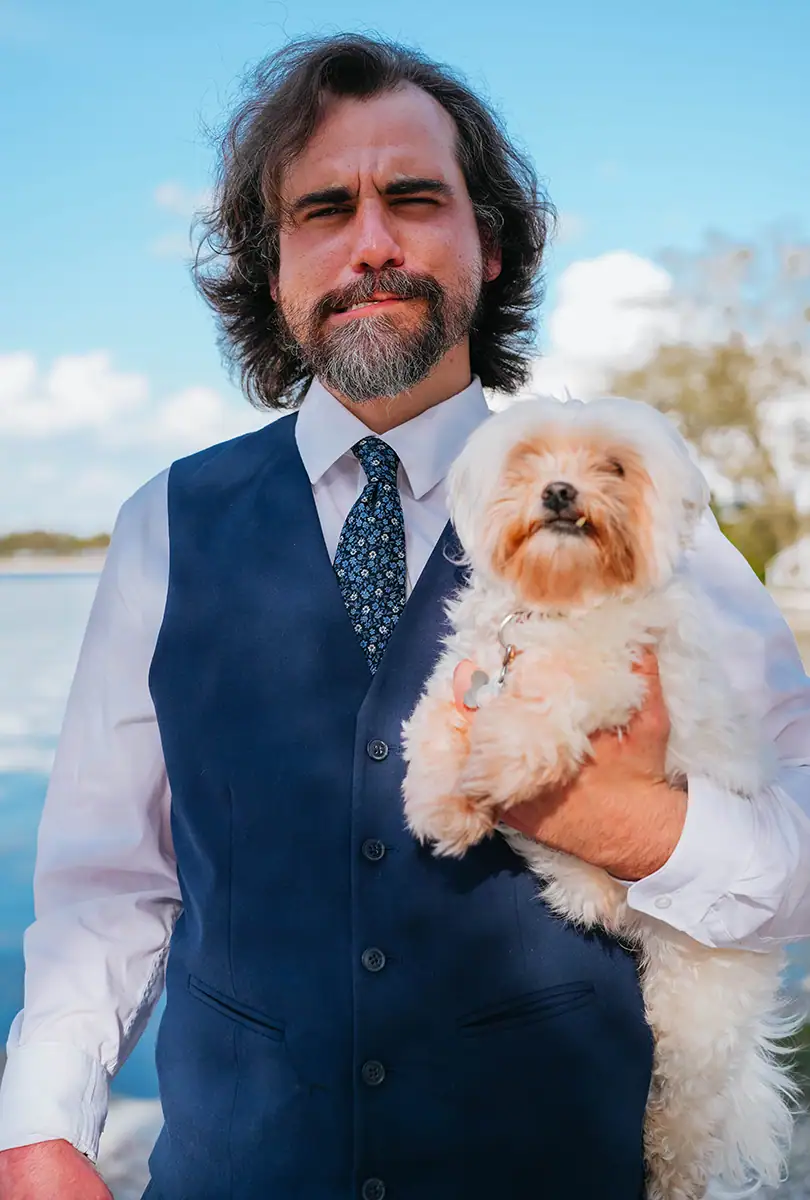 A man in a suit holding a white dog.