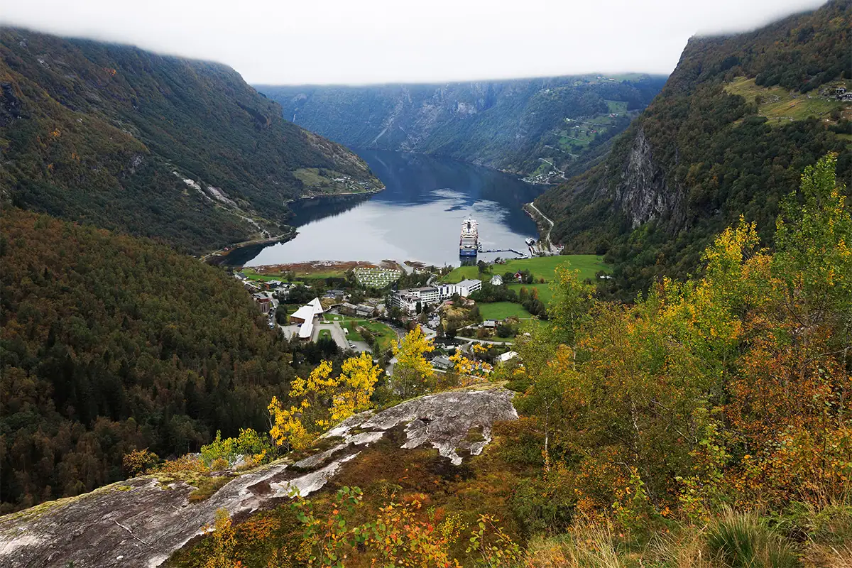 Norway fjord landscape viewed from above with autumn trees, mountains, and a cruise ship below