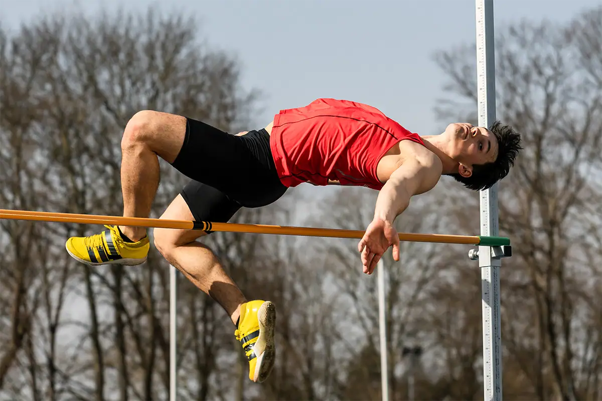 A high jumper clears the bar during an outdoor track and field event.