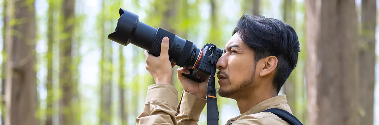 Photographer using a camera lens while exploring the difference between prime and zoom lens shooting styles.