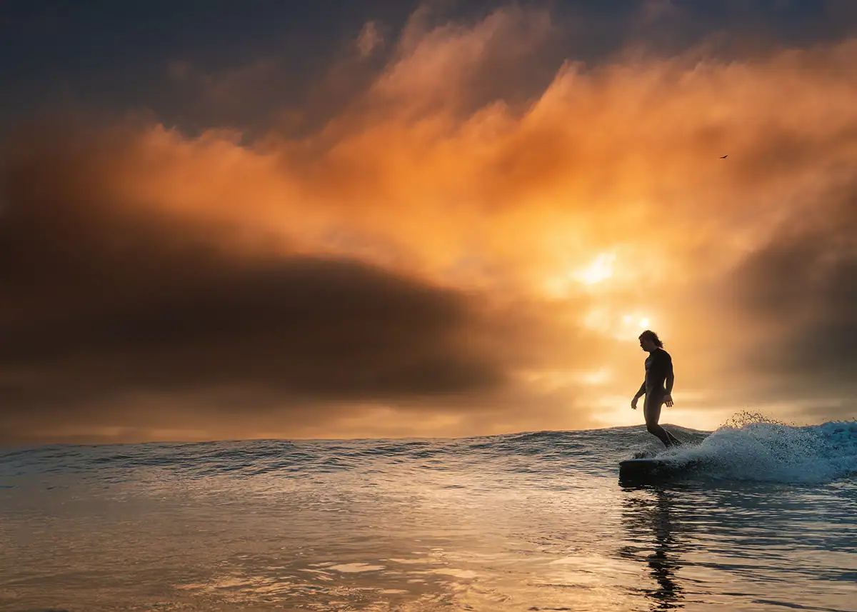 A surfer on his board at sunrise