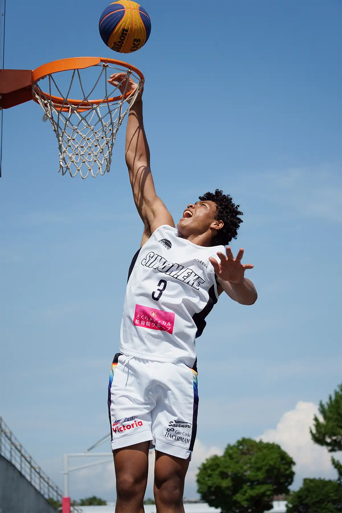 Basketball player reaching for the hoop during a decisive sports photography action moment.