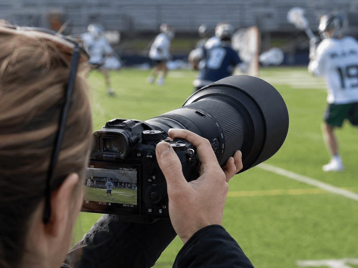 A photographer uses a Tamron 150-500mm telephoto zoom lens to track field sports action.