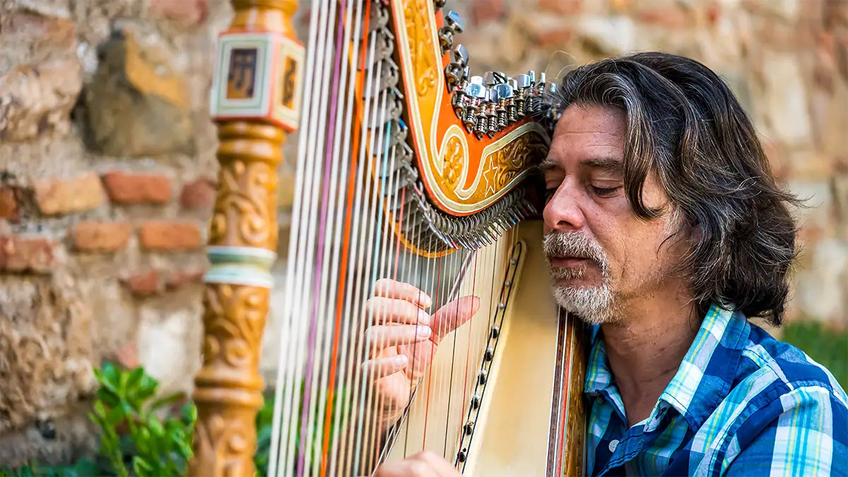 A harpist plays near Gibralfaro Castle in Spain, photographed with the Tamron 35-100mm F2.8 travel photography lens.