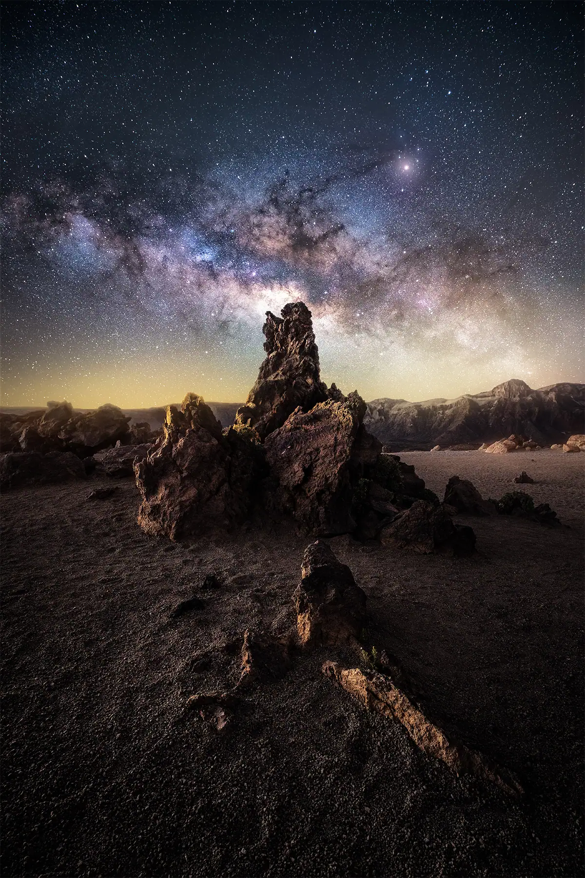 Wide-field Milky Way nightscape with a rock formation in the foreground for astrophotography composition.
