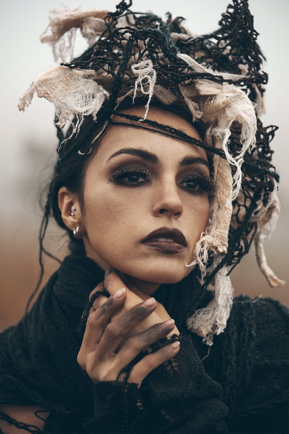 Close-up portrait of a woman wearing dramatic makeup and an intricate black-and-white textile headpiece.