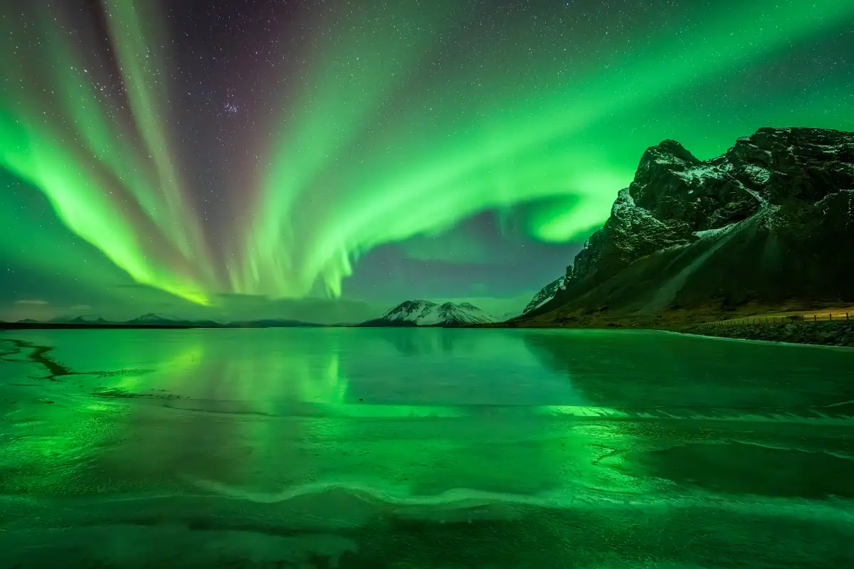 Aurora borealis over an icy lake and mountains photographed with the Tamron 12-20mm F2.8 for Nikon Z mount cameras.