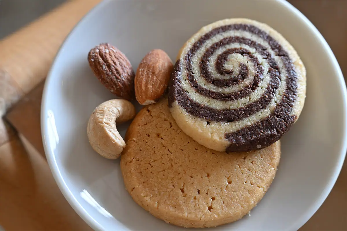 Fotografía gastronómica de una cafetería en la que se muestran galletas y nueces en un plato, con luz natural suave y poca profundidad de campo.