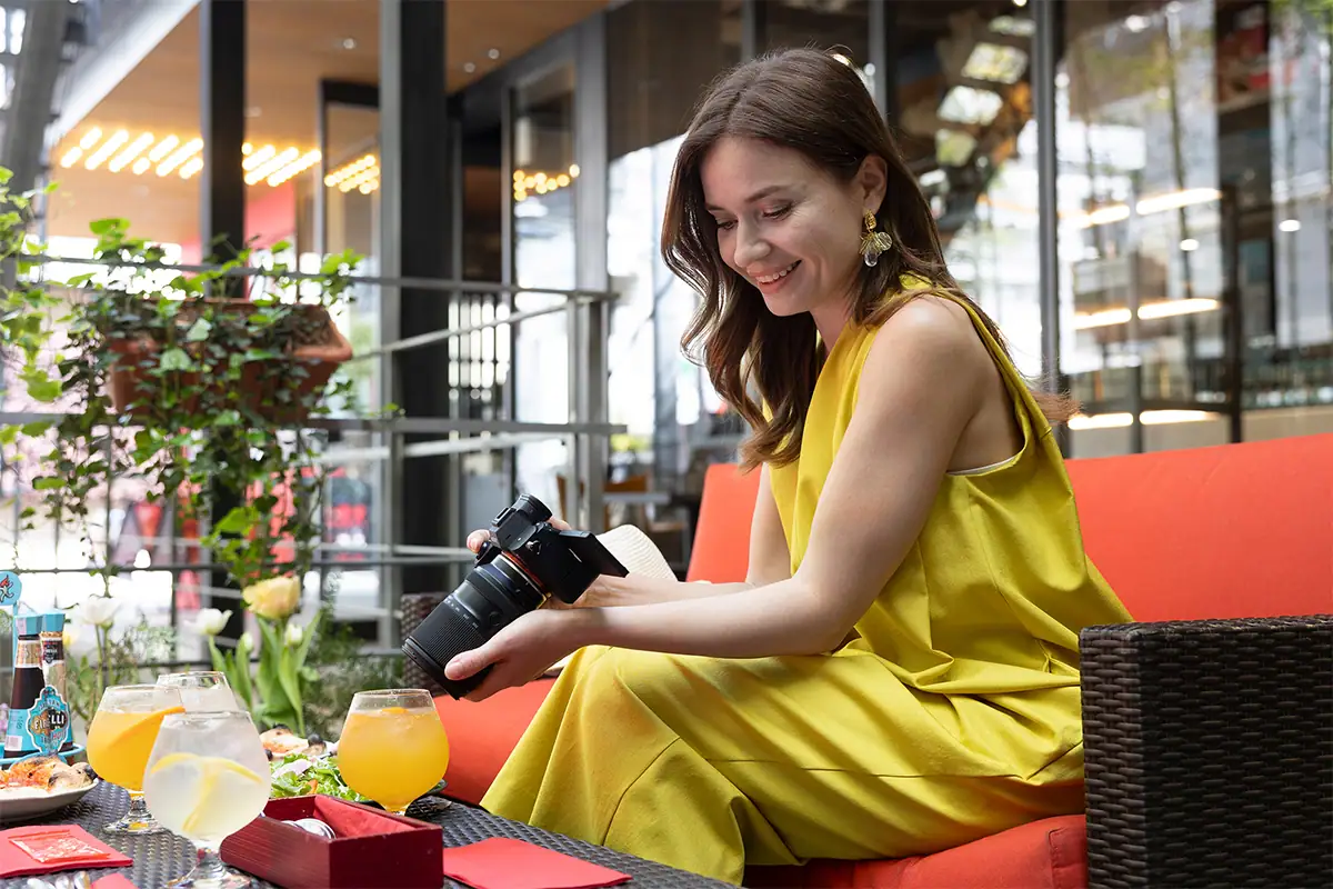 Fotógrafo que toma fotos de bebidas y comida en una cafetería con una cámara sin espejo y luz natural.
