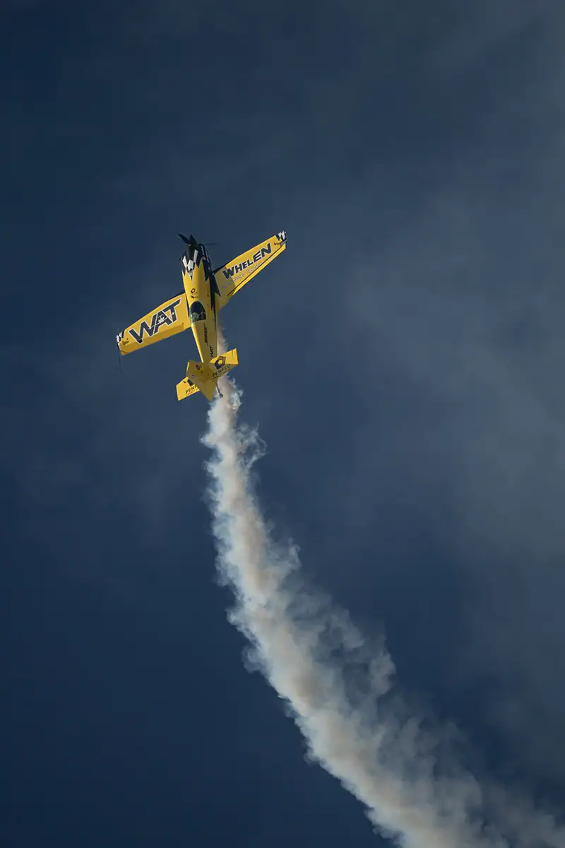 Un avion Wat-Whelen jaune se détachant sur un ciel qui s'assombrit.