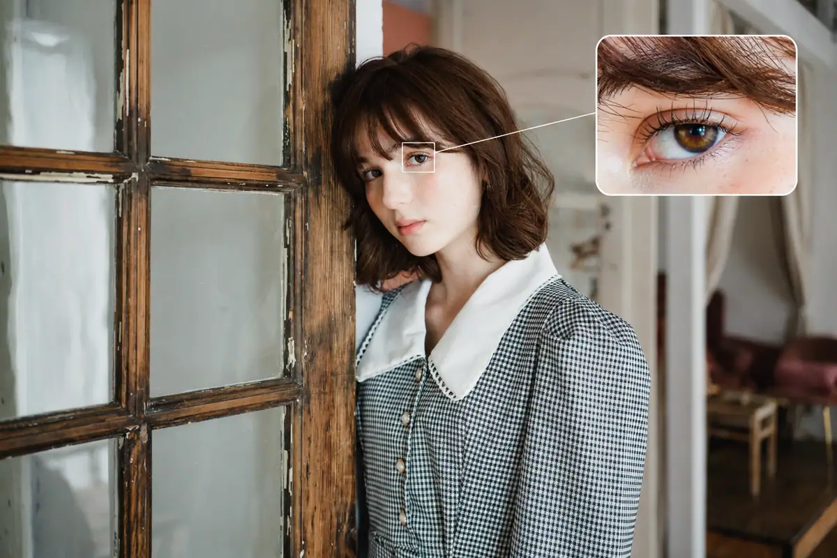Portrait of a woman indoors with the nearest eye sharply in focus and a photo-style inset highlighting the eye detail as seen through the camera.
