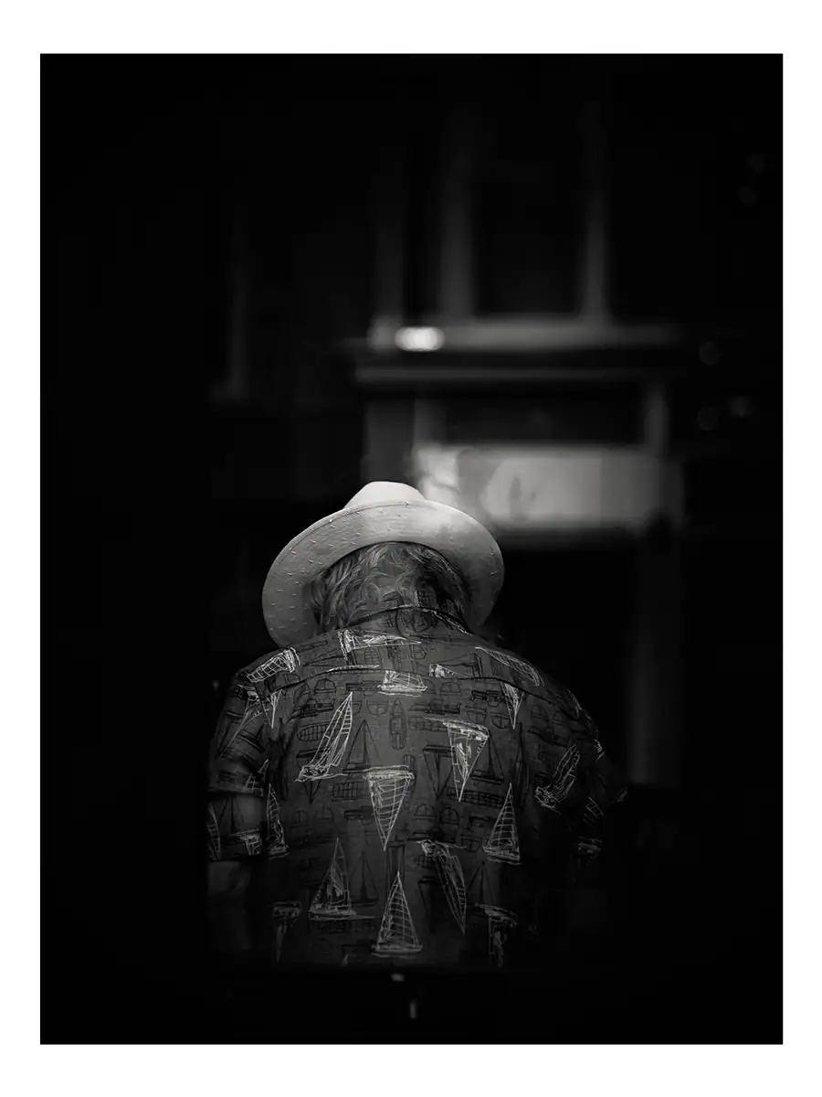 A person facing away wearing a hat and a shirt with sailboats