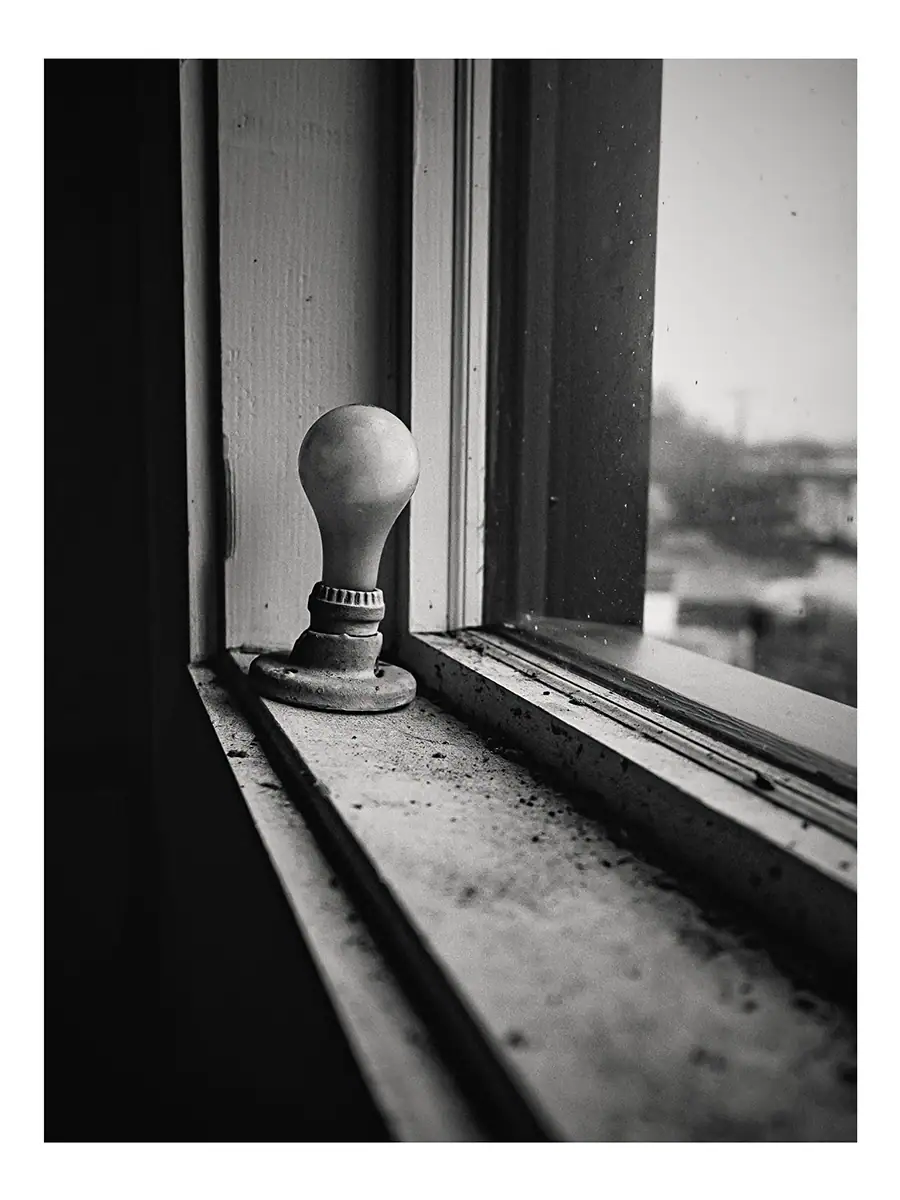 A lightbulb sitting on a dirty windowsill