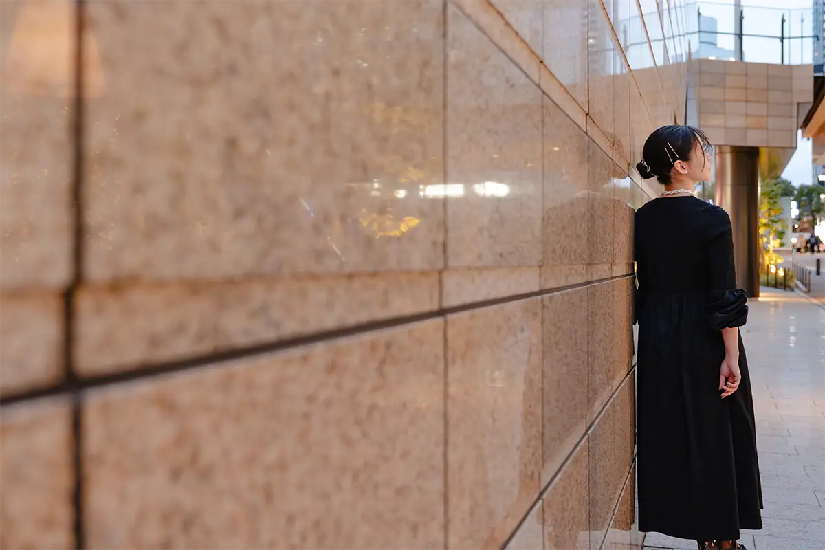 Woman in a black dress posing beside a reflective stone wall, photographed with the Tamron 17-70mm F2.8 for Nikon Z mount.