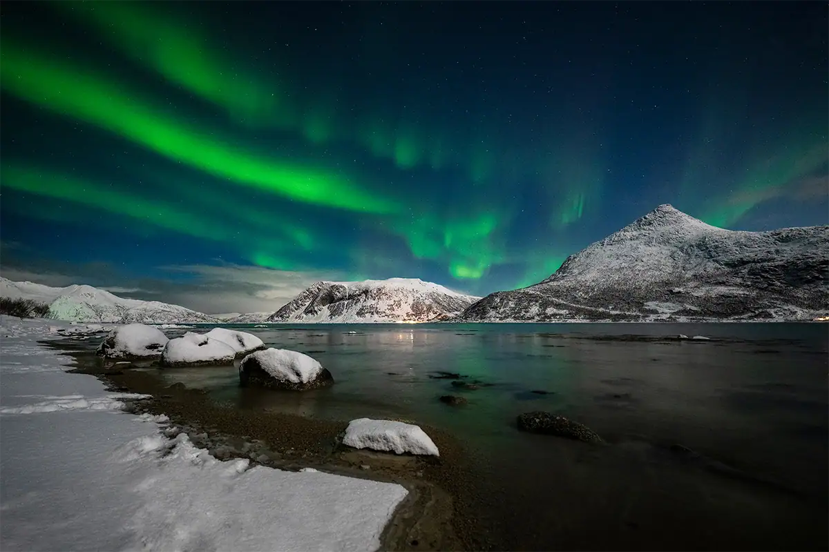 Aurora borealis over an icy lake and mountains photographed with the Tamron 12-20mm F2.8 for Nikon Z mount cameras.