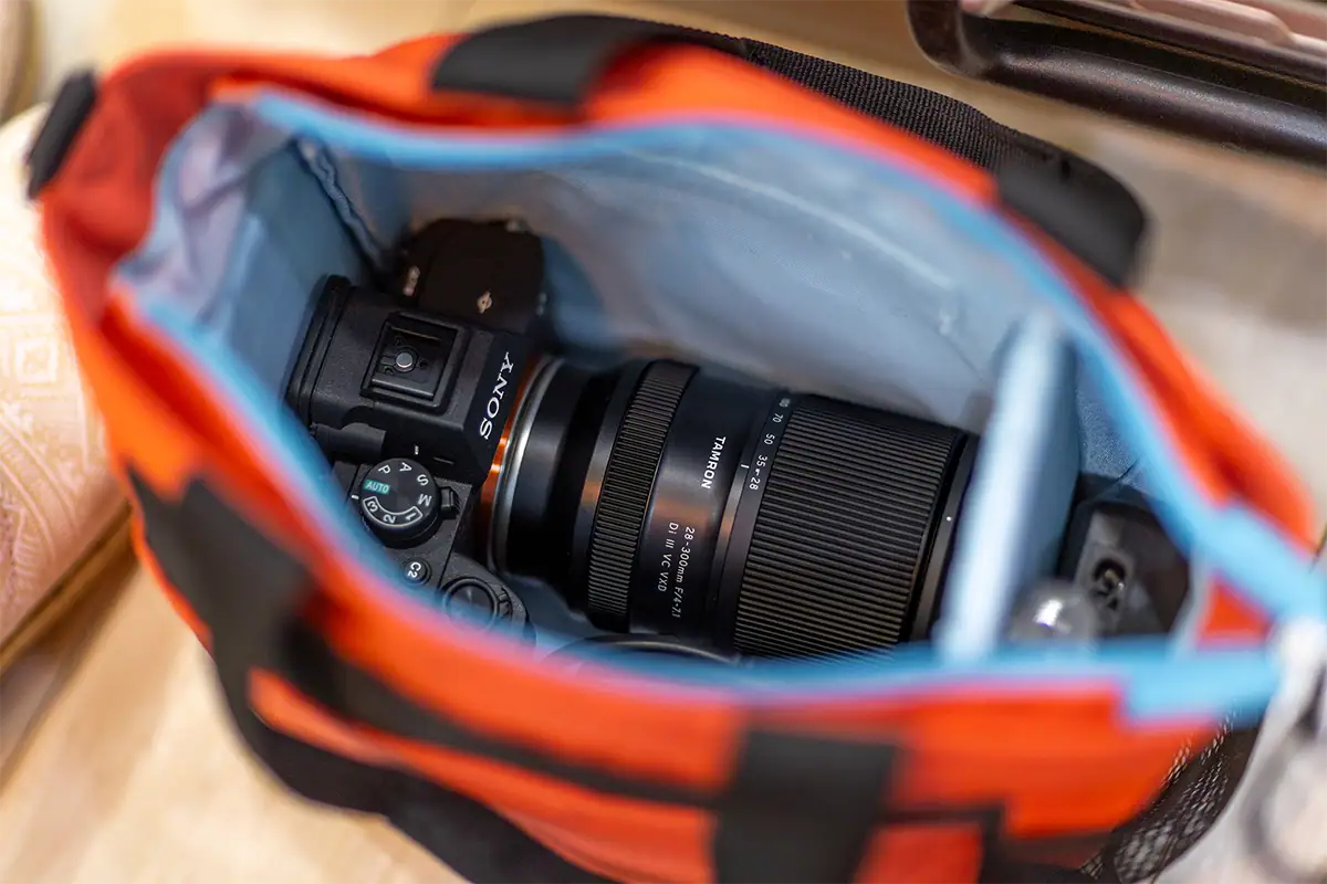 Tamron zoom lens mounted on a Sony camera and stored inside a padded camera bag for protected transport.