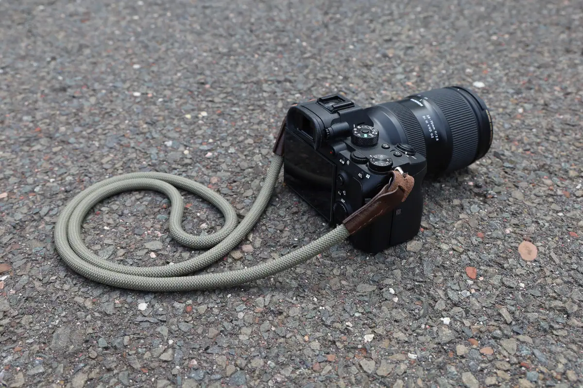 Sony camera with a Tamron lens attached to a rope-style camera strap for carrying photography gear.
