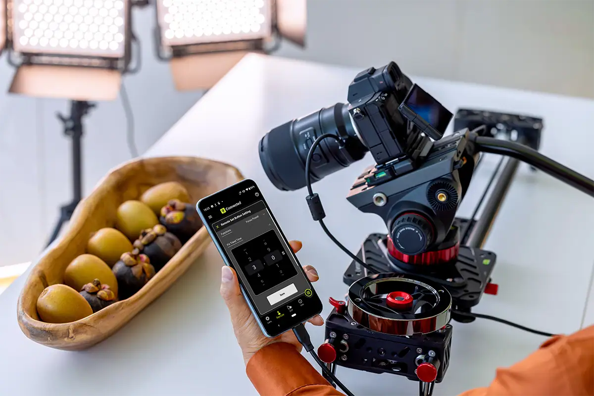 Câmera montada em um trilho de foco motorizado com luzes LED e controles por smartphone para fotografia macro precisa.