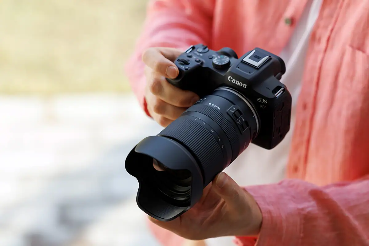Lente zoom padrão da Tamron montada em uma câmera sem espelho da Canon, mostrada na mão para ilustrar o tamanho, o equilíbrio e a manuseio geral do conjunto.