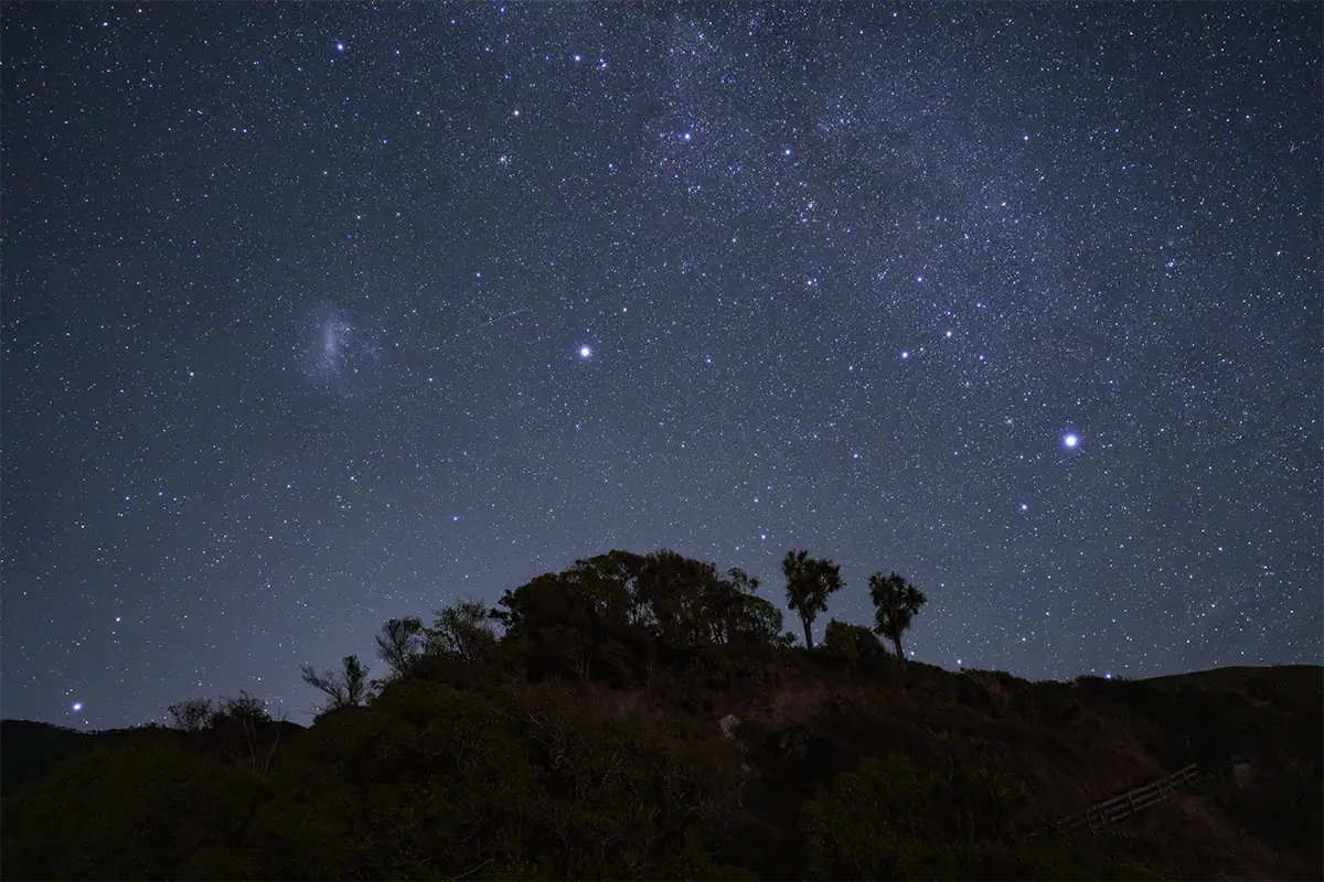 Sirius, Canopus et le Grand Nuage de Magellan au-dessus d'un paysage néo-zélandais en silhouette, photographié avec le Tamron 12-20 mm F2,8.
