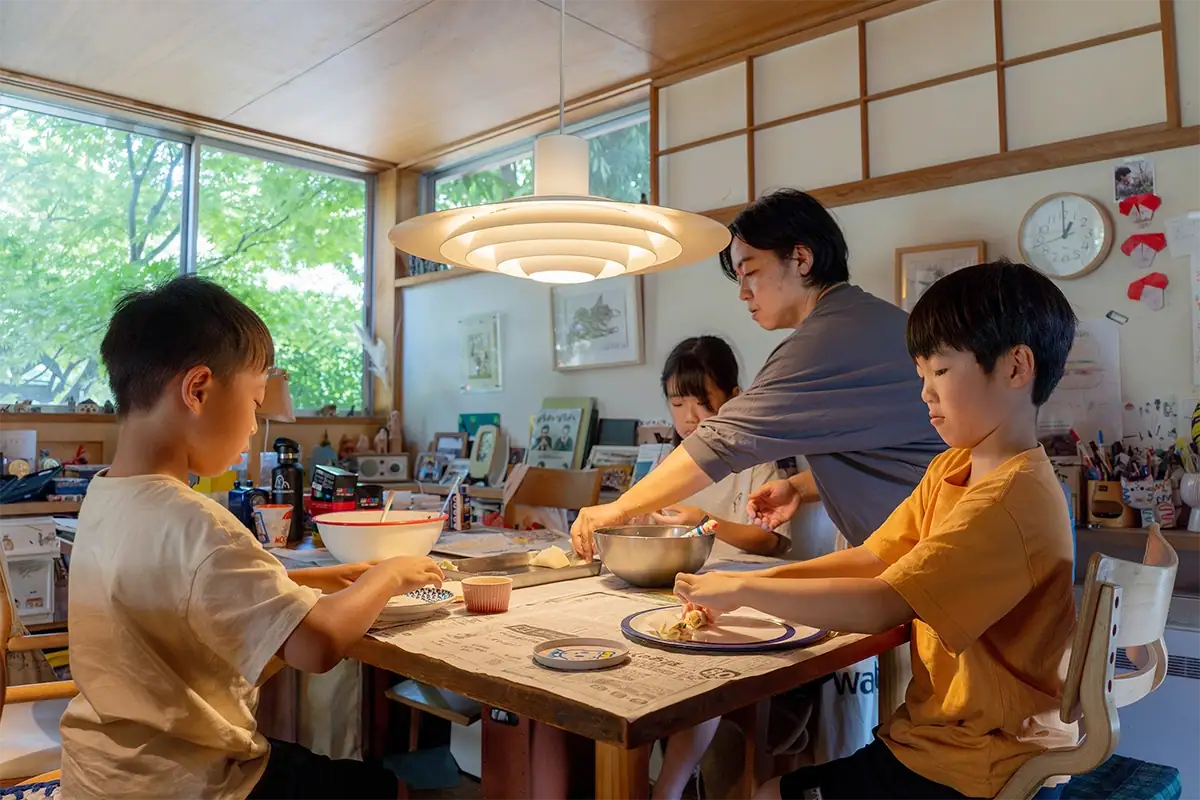 Família e amigos preparando gyoza juntos ao redor de uma mesa de jantar, em uma casa com iluminação aconchegante.