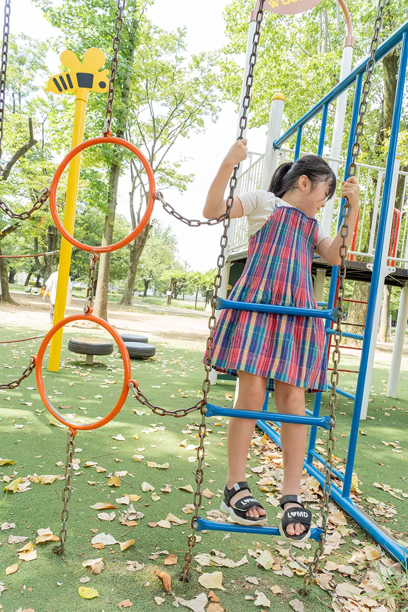 Menina escalando um brinquedo de playground ao ar livre, fotografada de cima com a Tamron 25-200 mm F2.8-5.6 G2.
