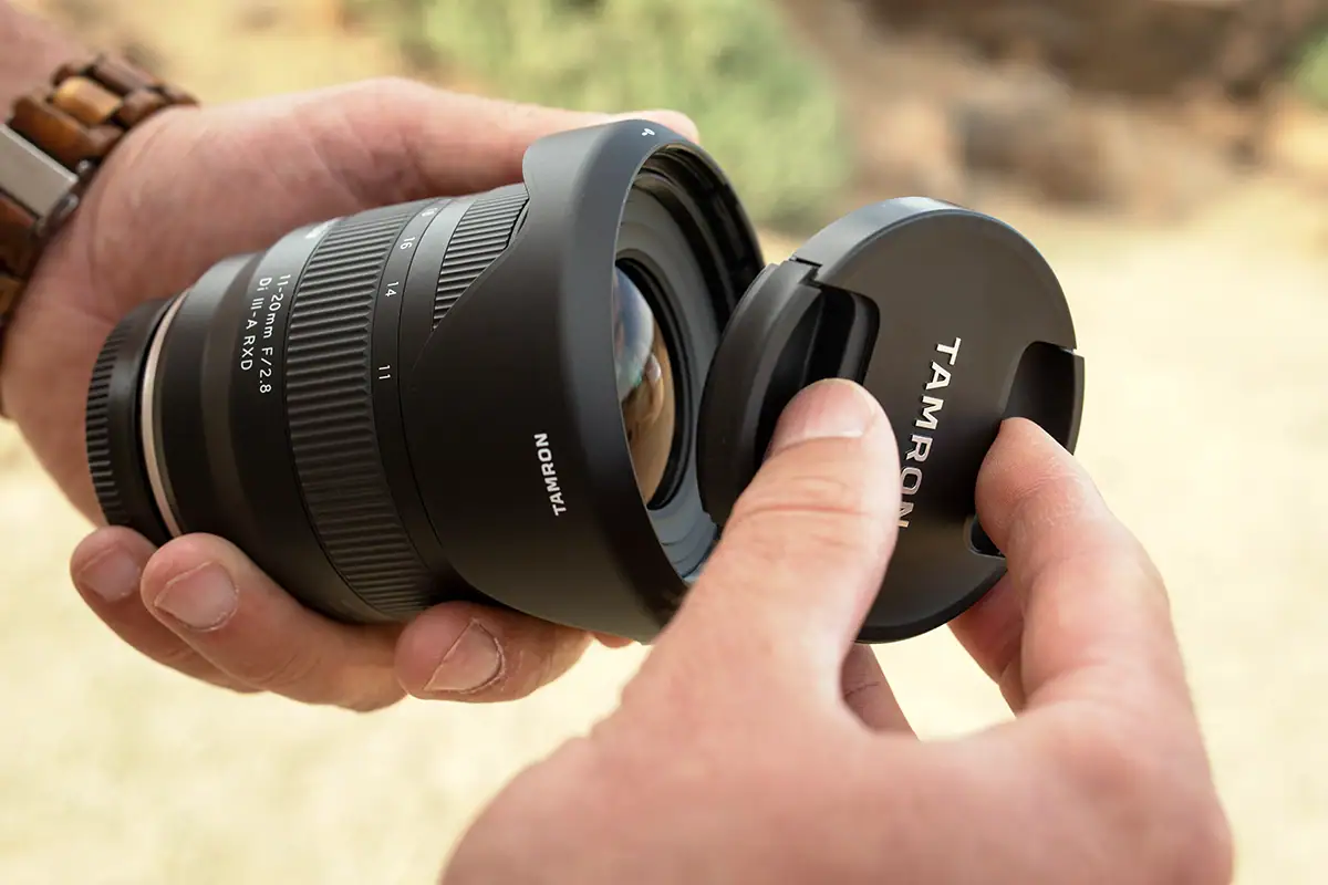 Tamron lens with lens hood attached as a front lens cap is being placed onto the lens.