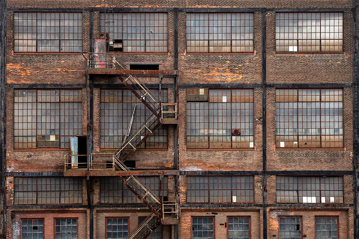 Weathered brick factory facade with repeating industrial windows and a zigzagging metal fire escape in Bethlehem, Pennsylvania.