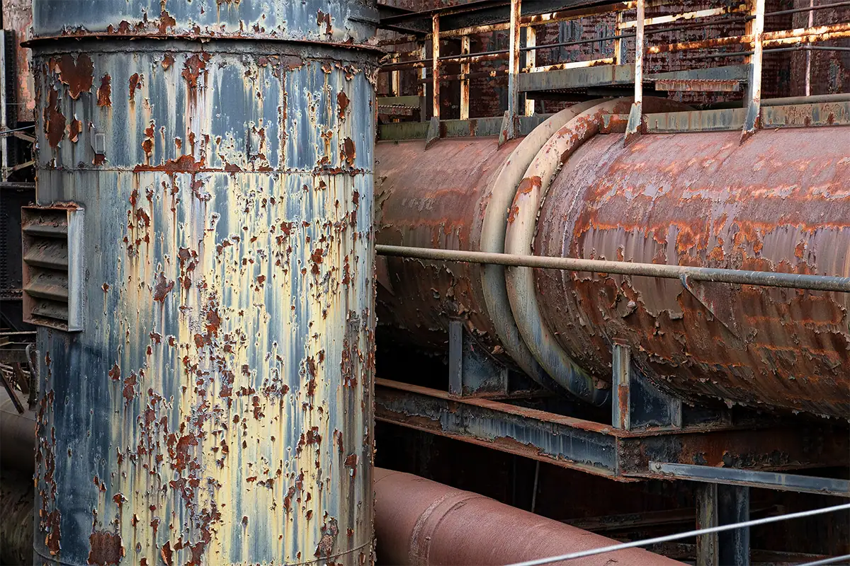 Close view of weathered industrial pipes with peeling paint and layers of rust at the Bethlehem Steel site.